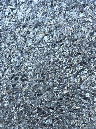 Silber zerknüllte Küchenfolie in Nahaufnahme, zerknitterte Grunge-Textur als Hintergrund. Glänzende, reflektierende Oberfläche aus zerknitterter Aluminium-Kochfolie mit Muster zufälliger Relieffalten.