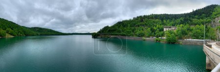 Photo for Lake Plastiras beautiful nature, panoramic view from the Dam to the green forested shores and the emerald water under darkening clouds. Man made Tavropos lake, Little Switzerland, Karditsa, Greece. - Royalty Free Image