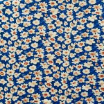 Fabric with a delicate floral pattern, close-up as texture. Old-fashioned cotton or linen textile in a retro style with a print of scattered colorful flowers. Bright floral background.
