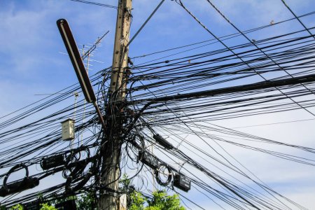 Tangled bundles of overhead wires. Electricity system on the streets of Thailand. Cable tangle on overloaded utilities pole in Thailand.
