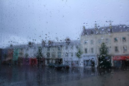 Téléchargez les photos : Regardant par la fenêtre de la vue en Angleterre au jour de pluie. Focus des gouttes de pluie dans la fenêtre avec un paysage urbain flou. Scène de voyage. - en image libre de droit