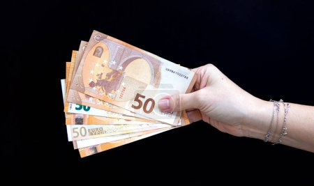Foto de Mano sosteniendo dinero con moneda euro aislada contra negro - Imagen libre de derechos