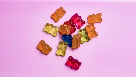 Téléchargez les photos : Bonbons gommeux ours colorés sur fond rose. Vue du dessus. - en image libre de droit