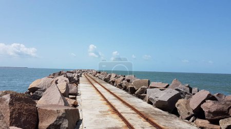 Photo for EXTENSIVE PIER ENTERING THE SEA AND BUILT WITH CEMENT AND WITH LATERAL SIDE BARRIERS OF HUGE STONES. - Royalty Free Image
