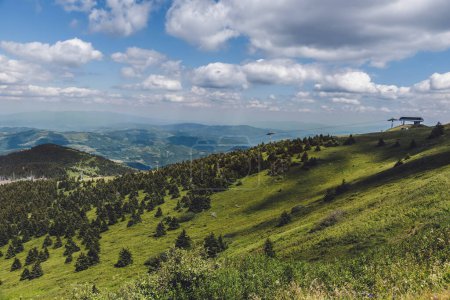 Foto de Paisaje de montaña en el Parque Nacional Kopaonik, reserva natural en Serbia. Vista panorámica de verdes colinas, laderas boscosas y denso bosque de coníferas bajo el cielo azul nublado. - Imagen libre de derechos