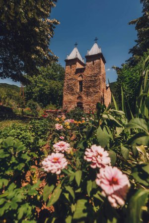 Photo for Church of Holy Mother of God is medieval Eastern Orthodox church in village of Donja Kamenica near Knjazevac. Historic Serbian church, architectural landmark surrounded by trees and flower garden. - Royalty Free Image