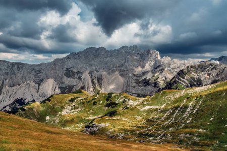 Foto de Paisaje montañoso con espectaculares nubes de tormenta sobre las montañas de los Alpes Dináricos en el Parque Nacional Durmitor, Montenegro. Paisaje alpino con contraste de lluvia y sol en verde valle montañoso en verano. - Imagen libre de derechos