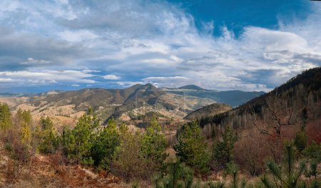 Mountain landscape in Zlatibor, Serbia. Panoramic view of green hills, mountains, wooded slopes and forest under blue cloudy sky on sunny autumn day.