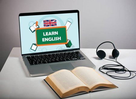 Photo for Laptop screen displayed learn English Poster and a book with headset in white table. isolated on gray background. selective focus image. - Royalty Free Image
