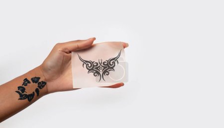 Téléchargez les photos : Main tenant le papier de tatouage temporaire isolé sur fond blanc doux. copier l'image espace - en image libre de droit