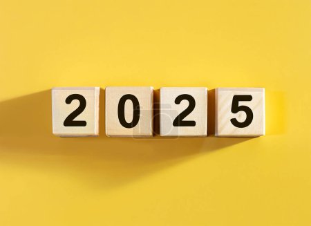 Téléchargez les photos : 2025 affiché sur des blocs de lettres en bois sur fond jaune pastel - en image libre de droit