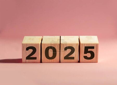 Téléchargez les photos : 2025 affichée sur des blocs de lettres en bois isolés sur fond rose pastel. - en image libre de droit