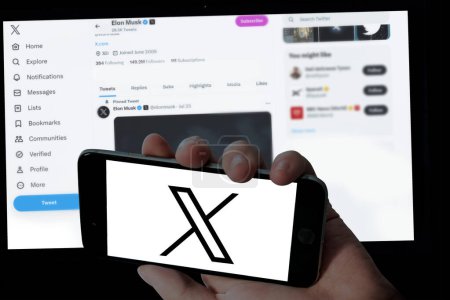 Foto de Logotipo de Twitter X en la celebración de móvil y Elon almizcle twitter página en fondo borroso pantalla del ordenador portátil - Imagen libre de derechos