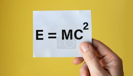 Foto de E igual a MC2 mostrado en papel de mano aislado sobre fondo amarillo liviano. - Imagen libre de derechos