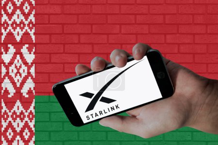 Téléchargez les photos : Logo Starlink affiché sur l'écran mobile et drapeau du Belarus avec fond de texture murale. - en image libre de droit