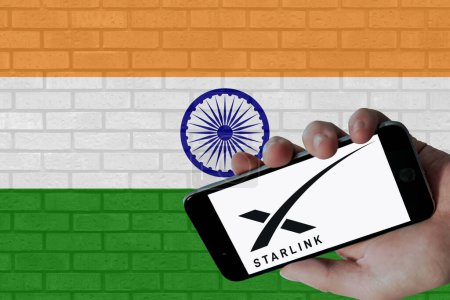Téléchargez les photos : Logo Starlink affiché sur écran mobile et drapeau de l'Inde avec fond de texture murale. - en image libre de droit