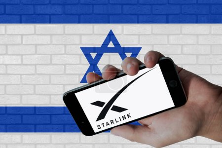 Téléchargez les photos : Logo Starlink affiché sur l'écran mobile et drapeau Israël avec fond de texture murale. - en image libre de droit