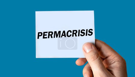 Photo for Permacrisis text displayed on hand holding paper isolated on blue background. - Royalty Free Image