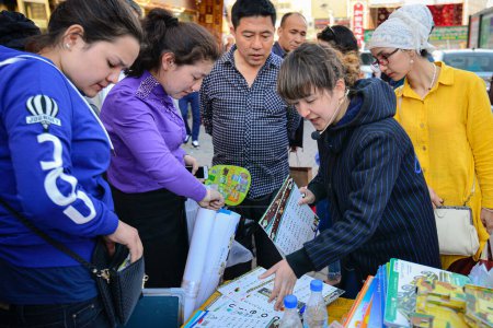 Foto de Vendedores que venden libros de ejercicios para niños y multitudes de espectadores en el mercado tradicional al aire libre en Urumqi, Xinjiang, China - Imagen libre de derechos