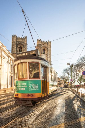 Foto de El legendario tranvía amarillo 28 corre en el casco antiguo de Lisboa, Alfama. Calles estrechas, antiguas casas coloridas, paisaje urbano de Portugal - Imagen libre de derechos