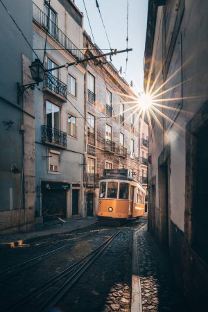 Foto de El legendario tranvía amarillo 28 corre en el casco antiguo de Lisboa, Alfama. Calles estrechas, antiguas casas coloridas, paisaje urbano de Portugal - Imagen libre de derechos