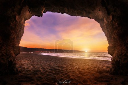 Foto de Salida o puesta del sol en Fuerteventura Islas Canarias. En la playa con piedras y larga exposición. luz única. Pura sensación de vacaciones. nubes finas - Imagen libre de derechos