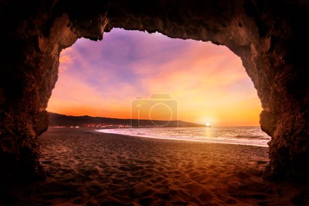 Foto de Salida o puesta del sol en Fuerteventura Islas Canarias. En la playa con piedras y larga exposición. luz única. Pura sensación de vacaciones. nubes finas - Imagen libre de derechos