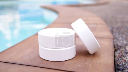 Photo for Tablet chlorine for swimming pool, white round chlorine on swimming pool background, chemical pool water maintenance - Royalty Free Image