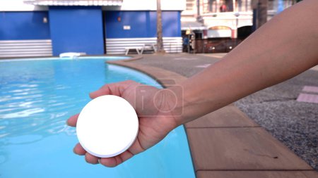 Photo for Female hand holding white round chlorine tablets, chlorine tablets for swimming pool maintenance. - Royalty Free Image