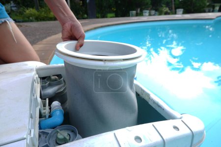 Female hand removing filter bag from  swimming pool filtration.