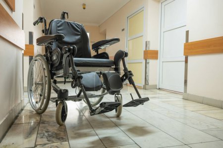 Téléchargez les photos : Lit médical postopératoire et fauteuil roulant sont situés dans le couloir du service hospitalier hospitalisé. Photo de haute qualité - en image libre de droit
