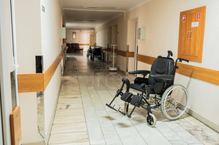 Lit médical postopératoire et fauteuil roulant sont situés dans le couloir du service hospitalier hospitalisé. Photo de haute qualité