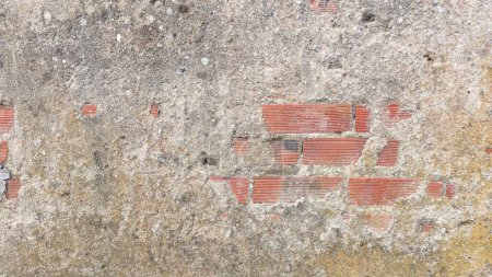 Téléchargez les photos : Plusieurs briques sont visibles sous l'ancienne couche de béton qui a commencé à s'effriter des pluies du soleil et du vent - en image libre de droit
