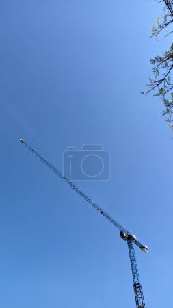 Téléchargez les photos : Grue de construction haute avec longue flèche sur ciel bleu - en image libre de droit