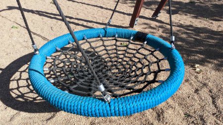 Téléchargez les photos : Balançoire dans le parc en corde noire et bleue en forme de nid d'oiseaux photo - en image libre de droit