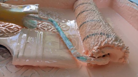 Téléchargez les photos : Rouleau et brosse sale dans le stand de peinture dans une baignoire de peinture photo - en image libre de droit