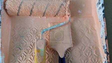 Téléchargez les photos : Rouleau et brosse sale dans le stand de peinture dans une baignoire de peinture photo - en image libre de droit