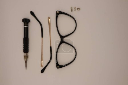Ein Meister repariert zerlegte Brillen und einen Schraubenzieher in der Nähe Foto