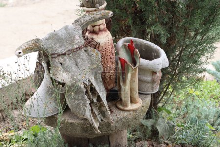 Kuhschädel mit Hörnern und Dekorationsgegenständen auf einem Steintisch im Garten Foto