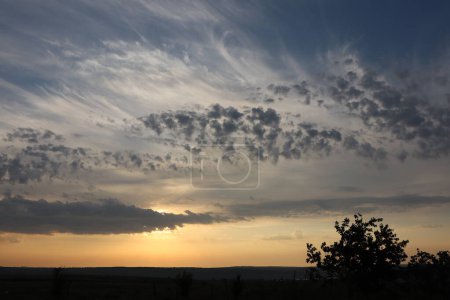 Evening sky over serene rural landscape shows stunning sunset with amazing clouds, creating beautiful peaceful scene