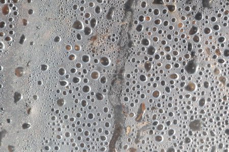 Closeup macro shot capturing water droplets on a metallic surface, revealing intricate textures and patterns
