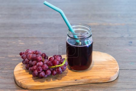 Photo for Fresh grapes and grape juice in jar with drinking straw on wooden board - Royalty Free Image
