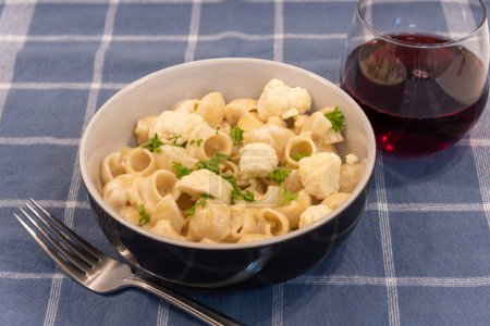 Foto de Pasta con coliflor y copa de vino en la mesa - Imagen libre de derechos