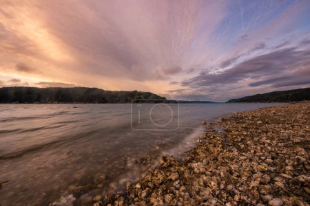 Foto de Vista panorámica de la playa rocosa en el lago bajo el cielo colorido atardecer - Imagen libre de derechos