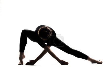 Téléchargez les photos : Une femme dans une pose de yoga asana avec les bras étendus sur un fond blanc. Photo de haute qualité - en image libre de droit