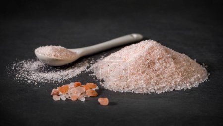 Foto de Una cuchara y un montón de sal rosa himalaya. Sal rosa y pimienta. Azúcar rosa. Especias para recetas foto - Imagen libre de derechos