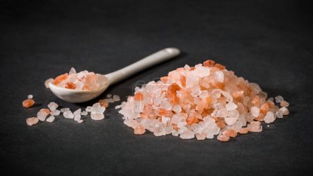 Téléchargez les photos : Une cuillère et une pile de cristaux de sel rose himalayen. Sel rose ou sucre. Des épices pour des recettes. Minéral. Photo de haute qualité - en image libre de droit