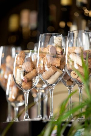 Téléchargez les photos : Rangée de verres à vin sur un bar avec des bouchons de bouteilles de vin à l'intérieur. Photo de haute qualité - en image libre de droit