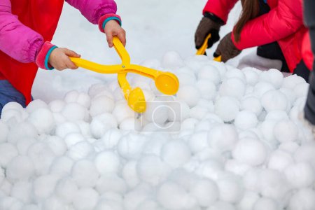 Téléchargez les photos : Enfants avec fabricant de boules de neige en plastique jaune pour s'amuser en hiver pendant les vacances sur neige. - en image libre de droit