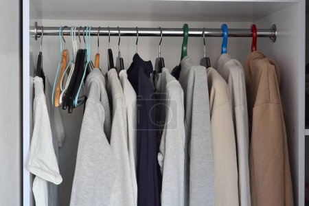 Photo for Men's light clothes hang on hangers in the closet - Royalty Free Image